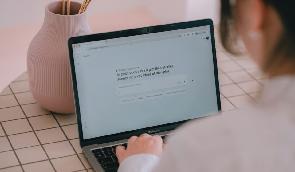 Woman typing on a laptop with a vase nearby