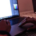 person using macbook pro on brown wooden table