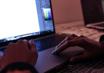 person using macbook pro on brown wooden table