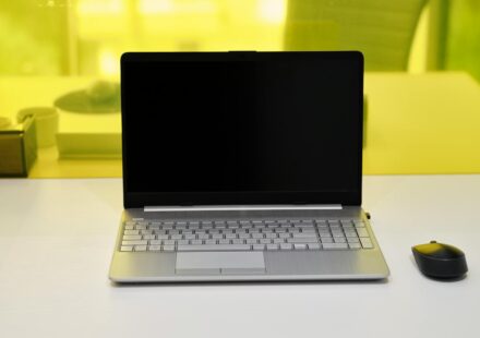 Sleek laptop with a blank screen and wireless mouse on a white desk.