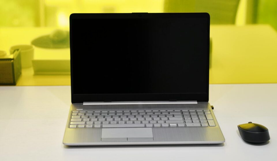 Sleek laptop with a blank screen and wireless mouse on a white desk.