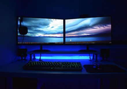 Dual monitors with blue lighting on a gaming desk setup.