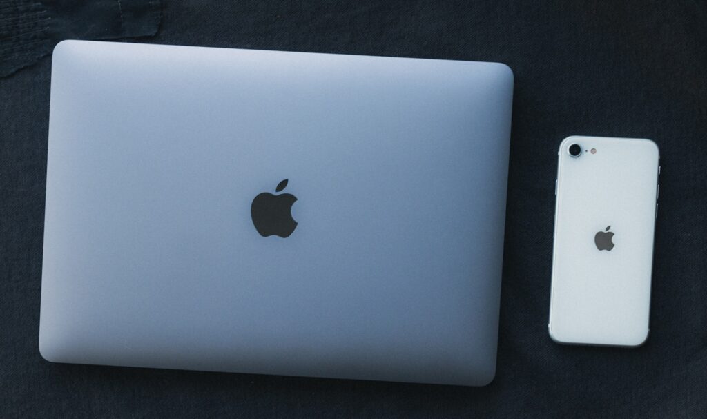 a white apple laptop next to a white iphone