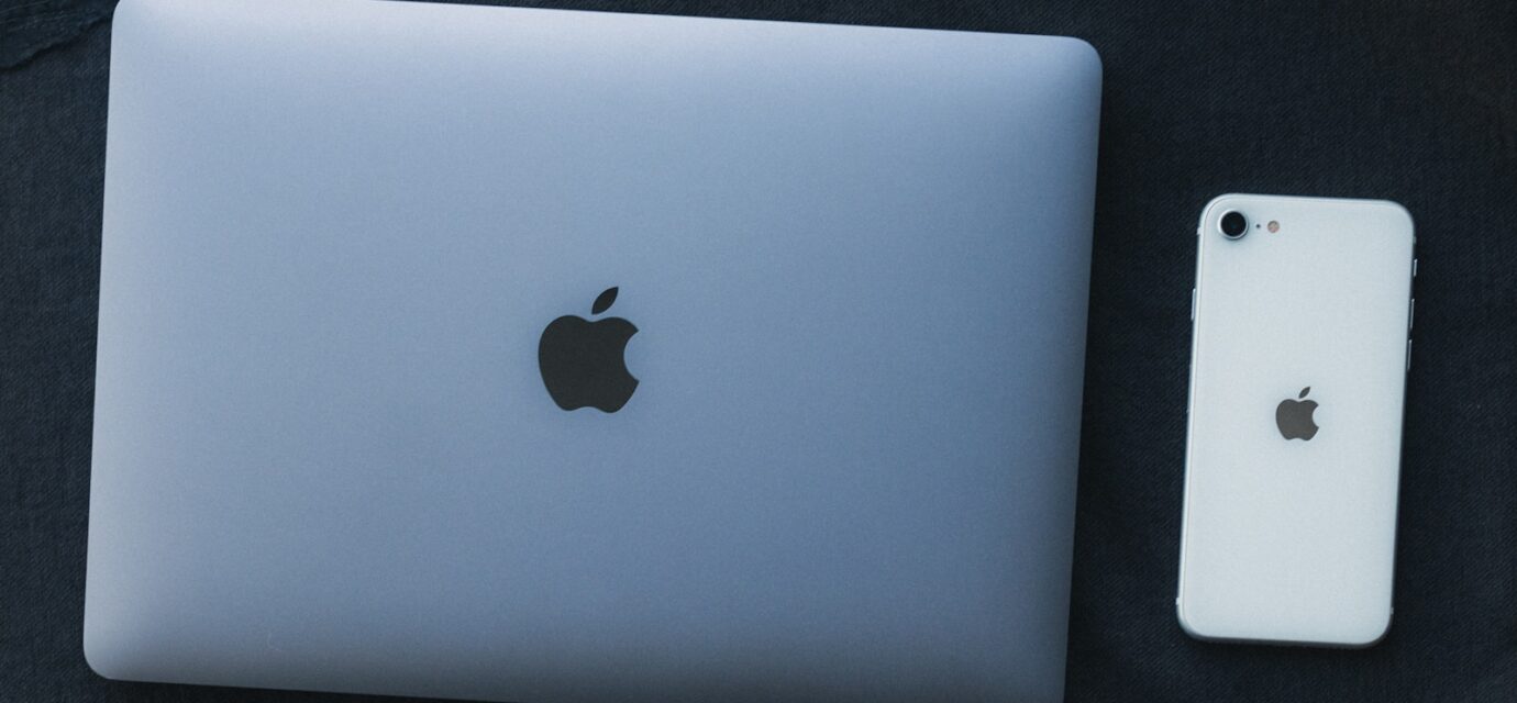 a white apple laptop next to a white iphone
