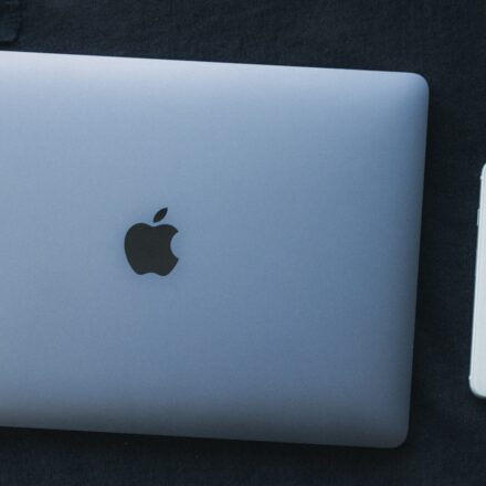 a white apple laptop next to a white iphone