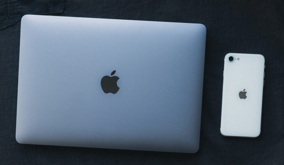 a white apple laptop next to a white iphone