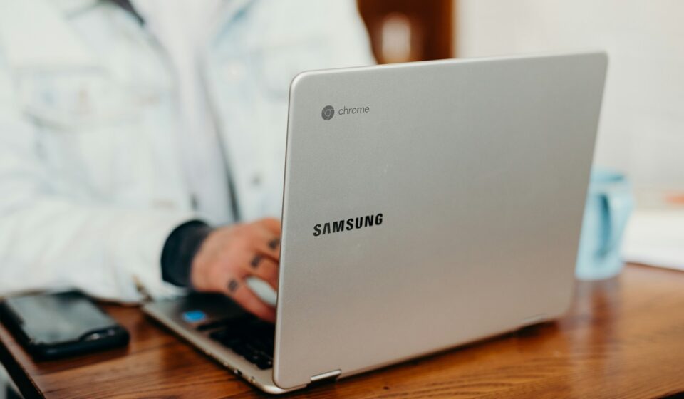 shallow focus photography of person using gray Samsung laptop