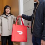 a woman holding a red bag standing next to a man