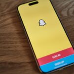 A yellow and blue iPhone sitting on top of a wooden table