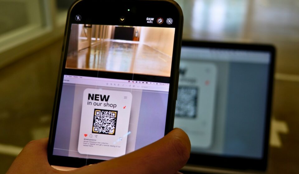 a person holding a cell phone in front of a laptop