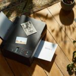 a printer sitting on top of a wooden floor next to a potted plant