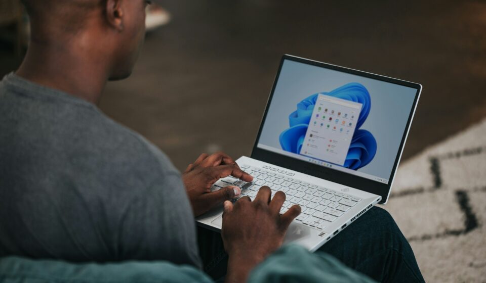 man in gray long sleeve shirt using Windows 11 computer